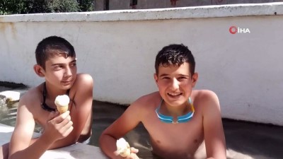  Sıcaklardan bunalan çocuklar köy meydanındaki su oluğunda serinliyor 